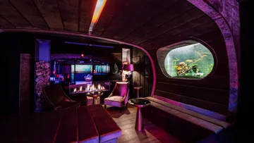 Lounge mit Sitzgelegenheiten, Kamin und Aquarium.