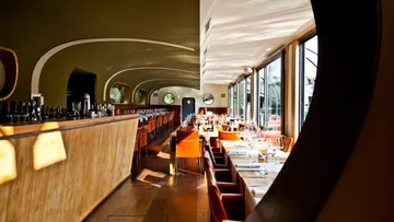 Moderne Restaurant-Inneneinrichtung mit Holztresen und Tischen.