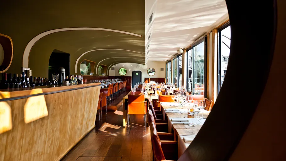 Modern restaurant interior with wooden bar and tables.