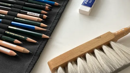 Bleistifte, Radiergummi und Pinsel auf einem Tisch.