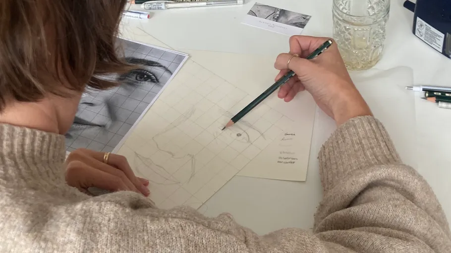 Person zeichnet Porträt mit Bleistift auf Papier.
