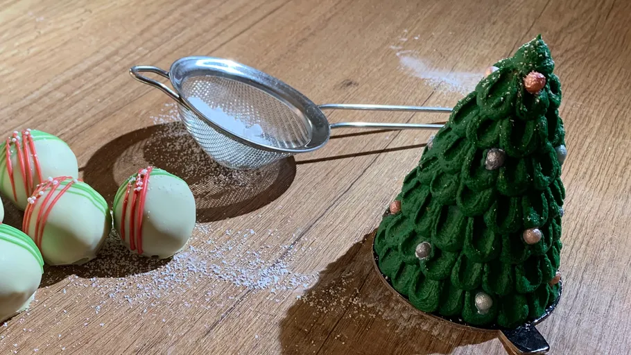 Christmas pastries and sieve on wooden surface.