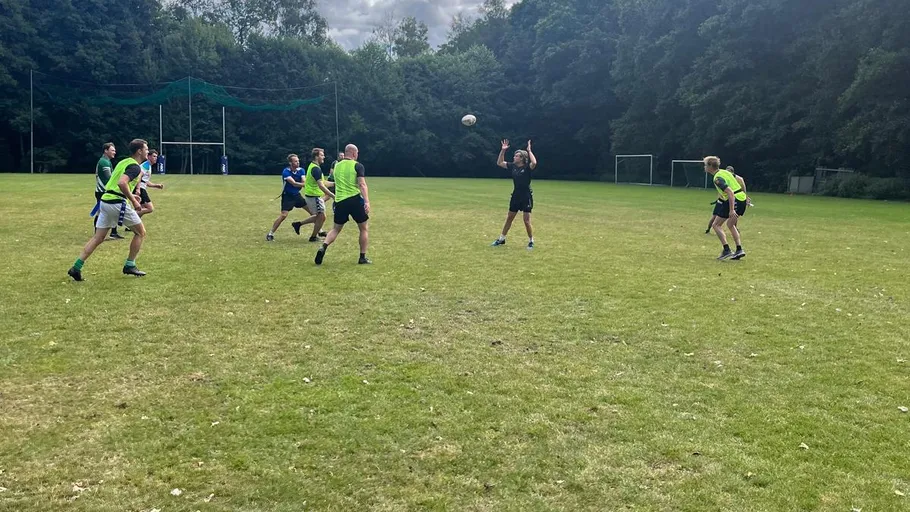 Leute spielen Rugby auf einem Rasenfeld.