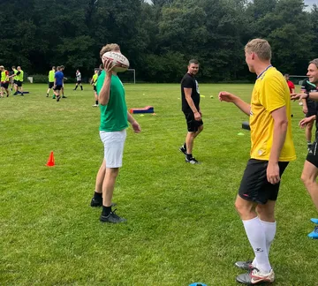 Group playing rugby on a grassy field.