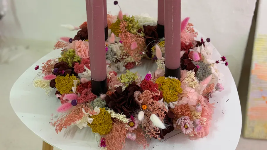 Floral wreath with pink candles on table.