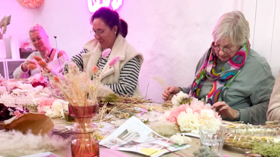 Women crafting flower arrangements on table.