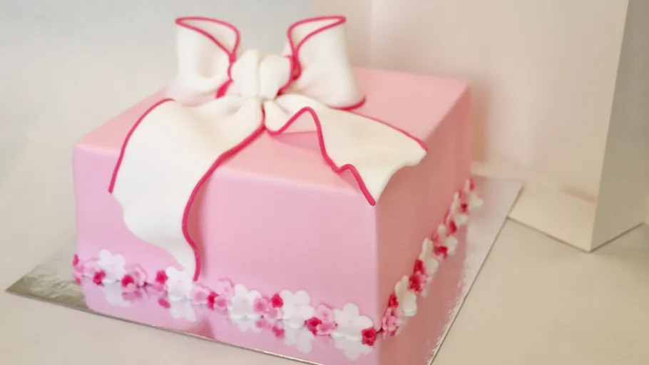 Pink cake with white bow decoration.