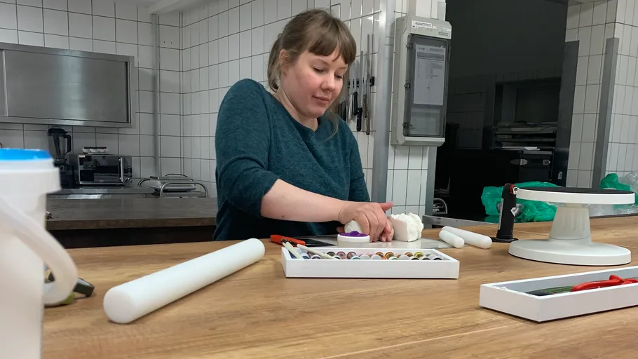 Woman decorating cake in a kitchen.