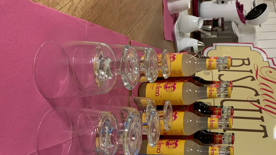 Bottles and glasses on a pink tablecloth.