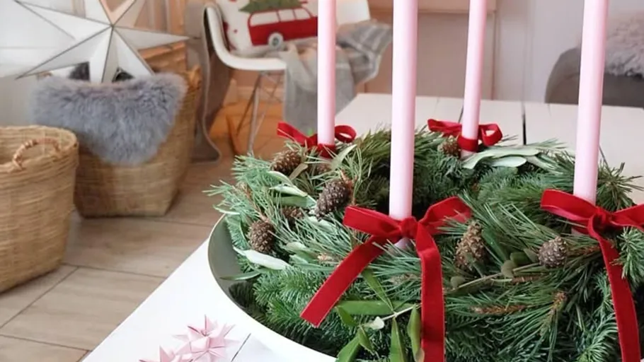 Advent wreath with pink candles on table.