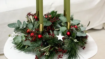 Green candles in Christmas wreath on table.