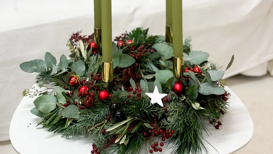 Green candles in Christmas wreath on table.