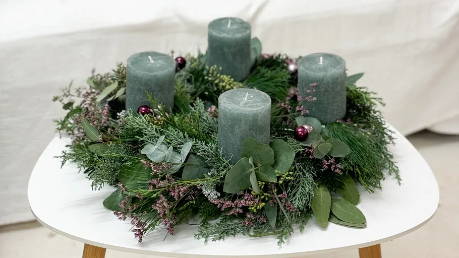 Green candles on a decorative foliage wreath.