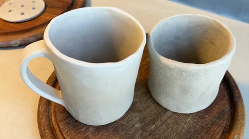 Two clay mugs on wooden surface.