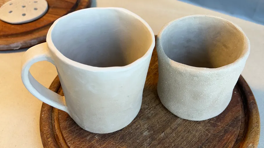 Two clay mugs on wooden surface.