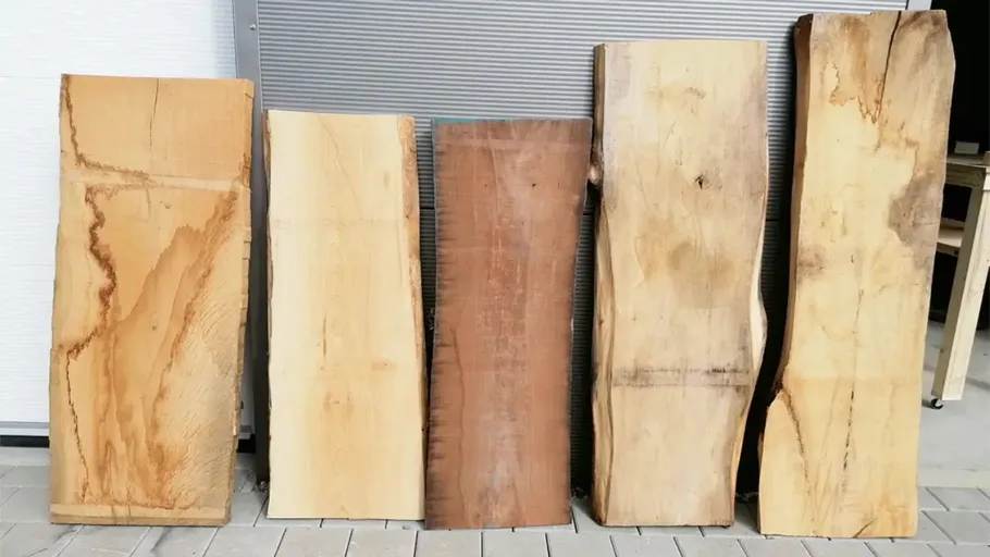 Fünf Holzplatten lehnen an einer Wand.