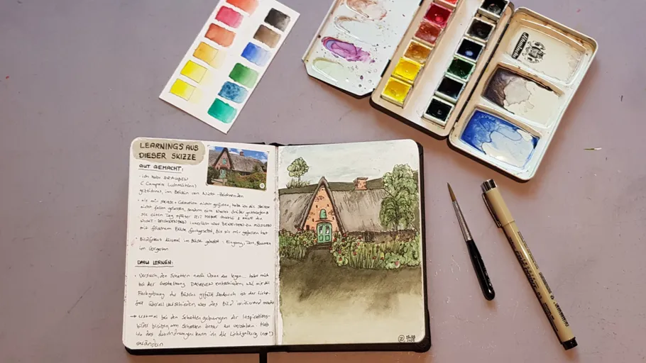 Sketchbook with countryside drawing and watercolors.