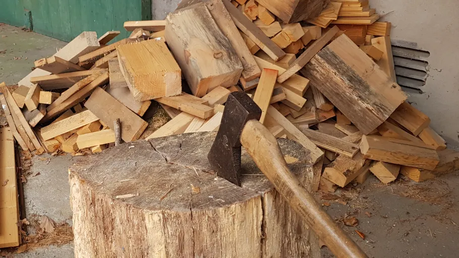 Axe on stump with stacked firewood.