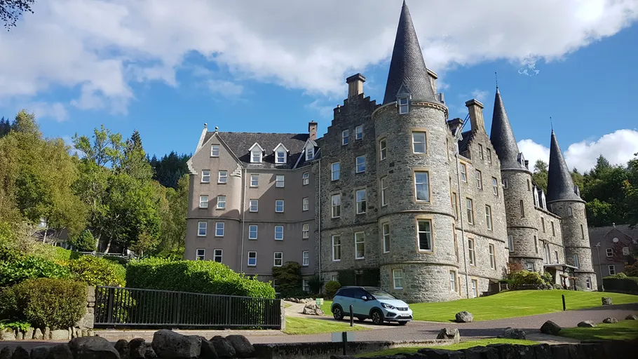 Stone castle with towers, grassy lawn, blue sky.