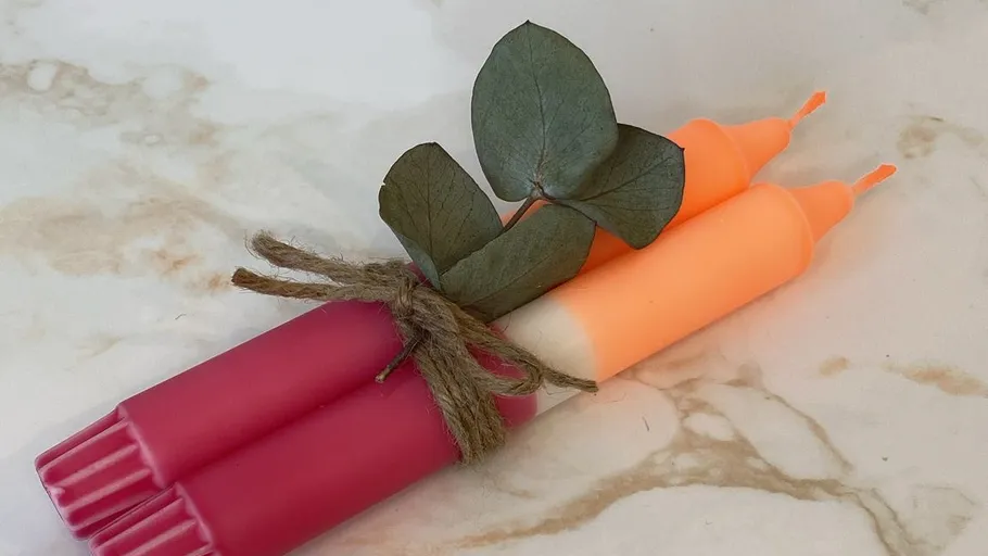 Rosa und orange Kerzen mit Blättern gebunden.