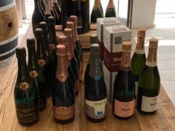 Bottles of sparkling wine are placed on a wooden table.