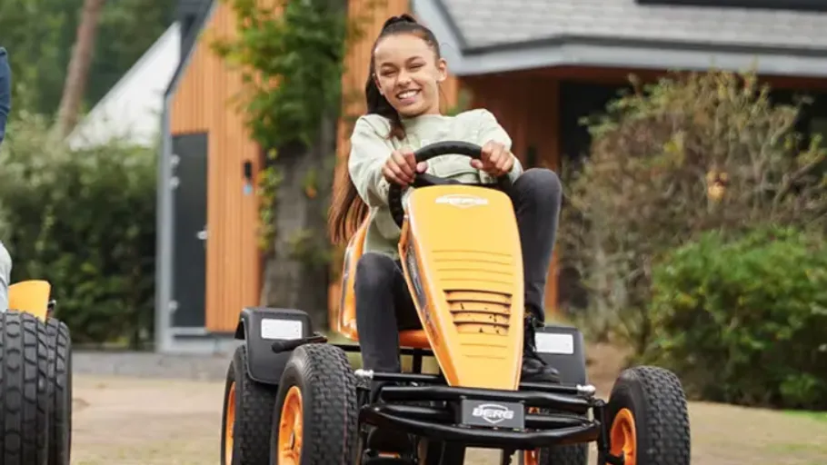 Two people riding go-karts outdoors.