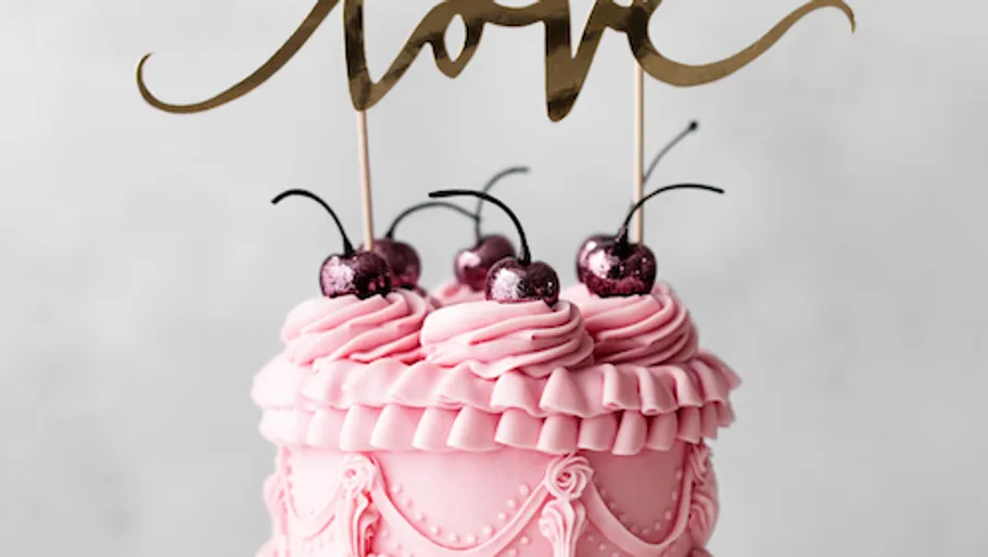 Rosa Kuchen mit Kirschen und goldener Topper.