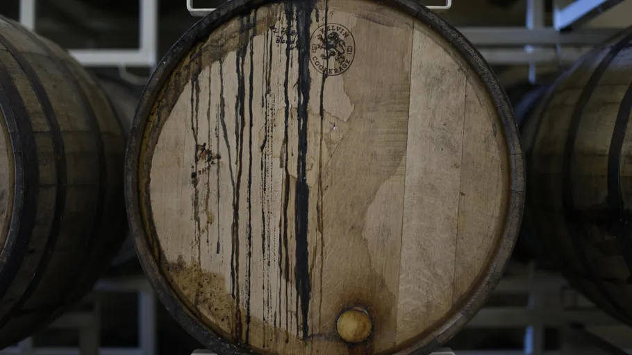 Holzfass mit Flüssigkeitsflecken im Keller.