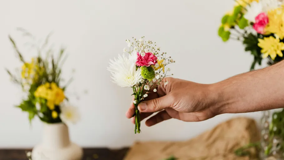 Hand hält kleinen Blumenstrauß drinnen.