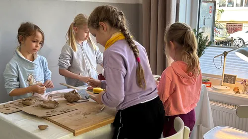 Kinder formen Ton an einem Tisch drinnen.