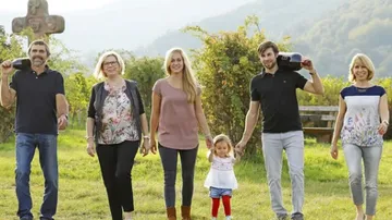 Six people walking in a green field.