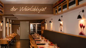 Restaurant-Innenraum mit Tischen und Weinlagerung.