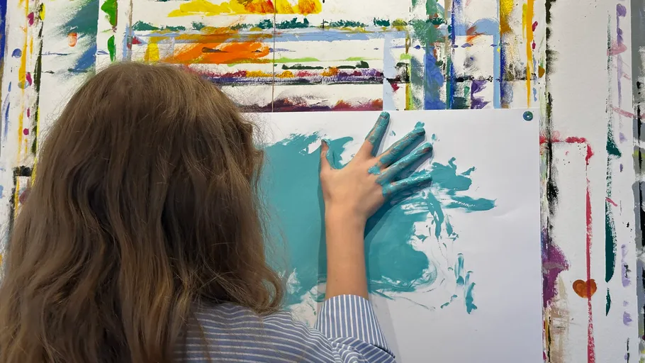 Child painting with hand in art studio.