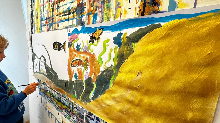 Kind malt buntes Kunstwerk auf großer Leinwand.