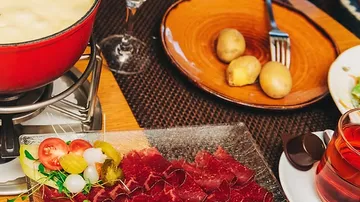 Käsefondue mit Beilagen auf dem Tisch.