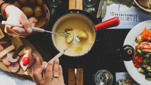 Two people enjoying cheese fondue meal.