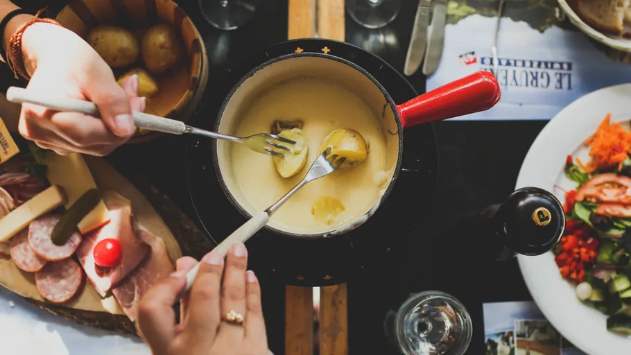 Two people enjoying cheese fondue meal.