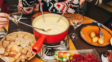 People enjoying cheese fondue at dining table.