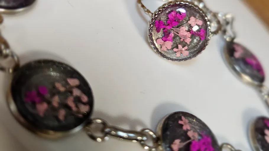 Armband mit rosa Blumen, silberner Hintergrund.