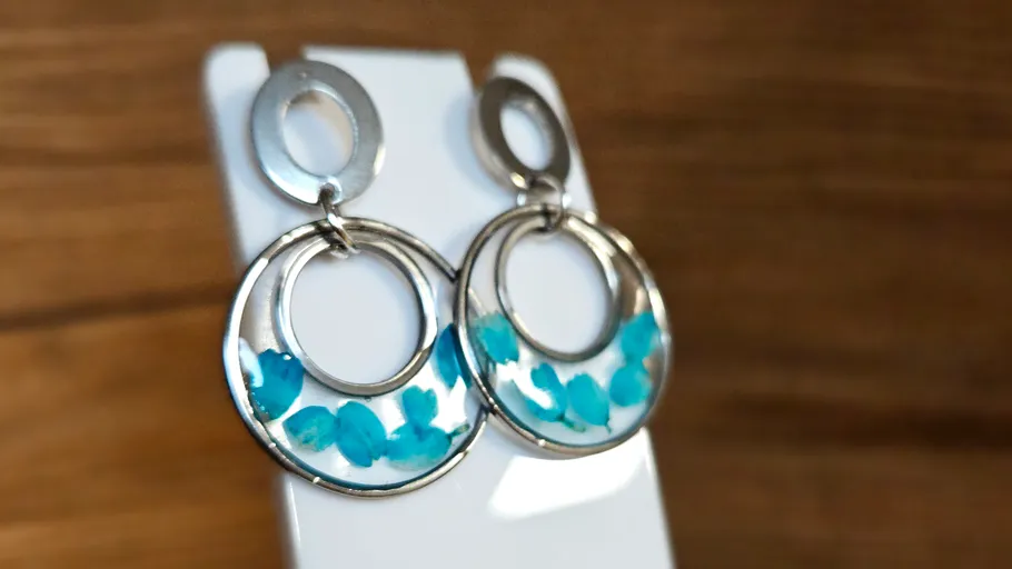 Silver earrings with blue details on display.