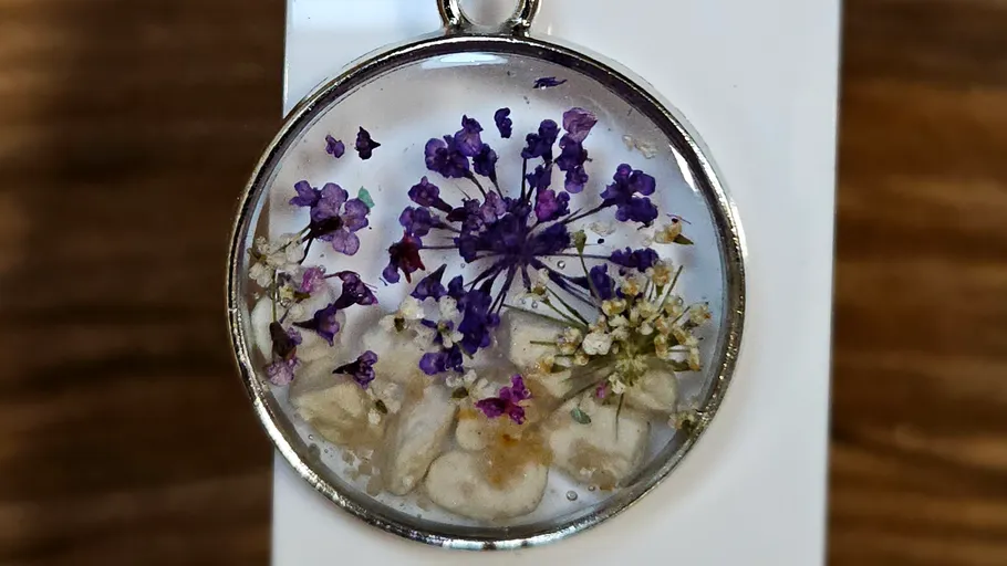 Round pendant with purple flowers inside.