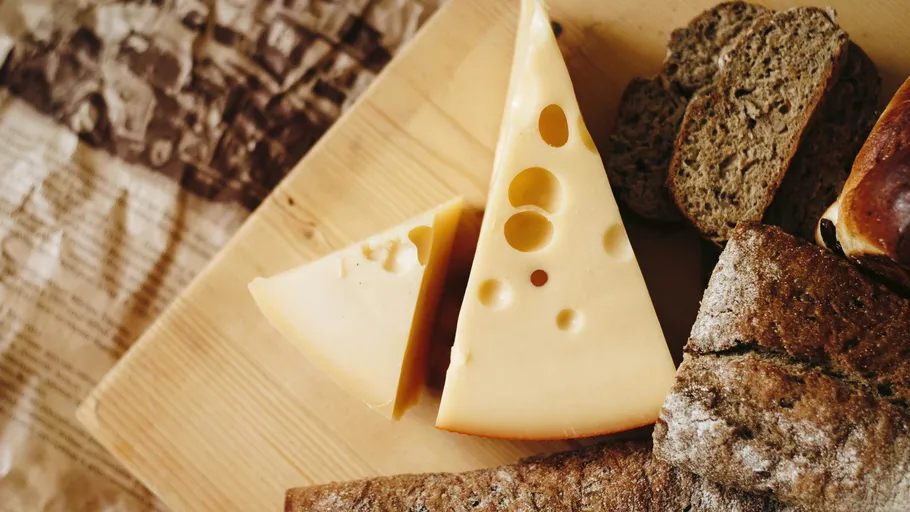 Cheese and bread on wooden cutting board.