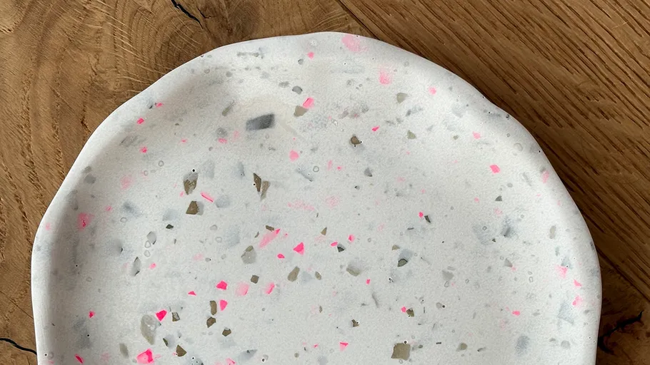 Speckled white plate on wooden surface.