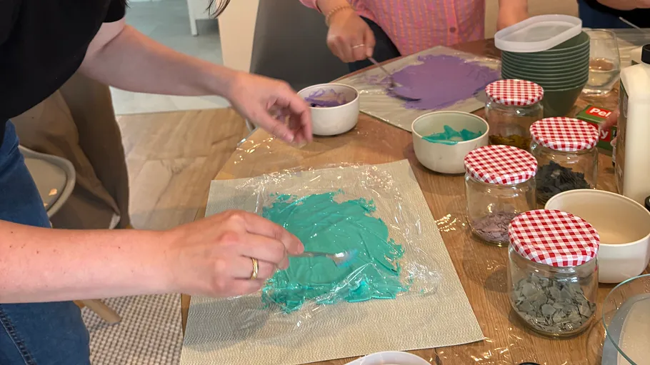 Person verteilt türkisfarbene Farbe auf Plastikfolie.