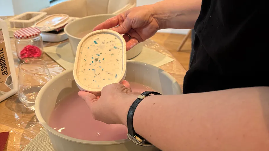 Person holding craft item over basin.