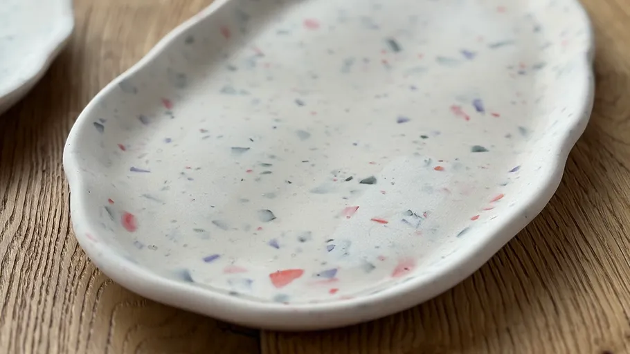 Speckled ceramic plate on wooden surface.