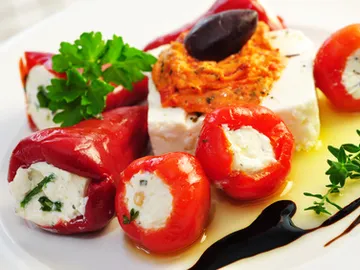 Stuffed peppers and tomatoes on a white plate.
