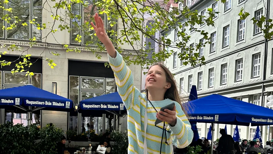 Girl reaching up in a city square.