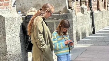 Two women and a girl on a sidewalk.