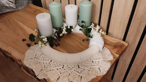 Decorative wreath with candles on wooden table.